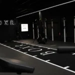 BOXR gym interior with black turf and ski machines.