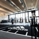 Bright Adidas gym with squat racks and floor logo.