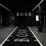 Dark gym with BOXR logo on wall and floor turf.