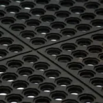 Detail of four interlocking black rubber drainage mats.
