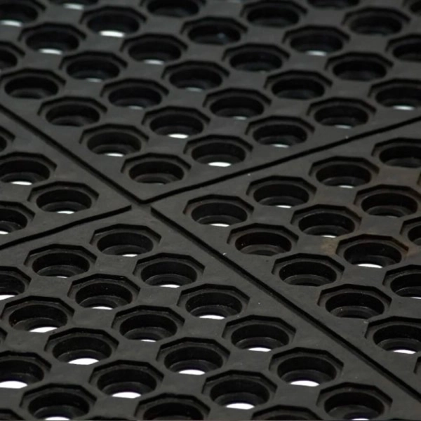 Detail of four interlocking black rubber drainage mats.