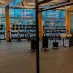 Modern gym interior with weights and large windows.