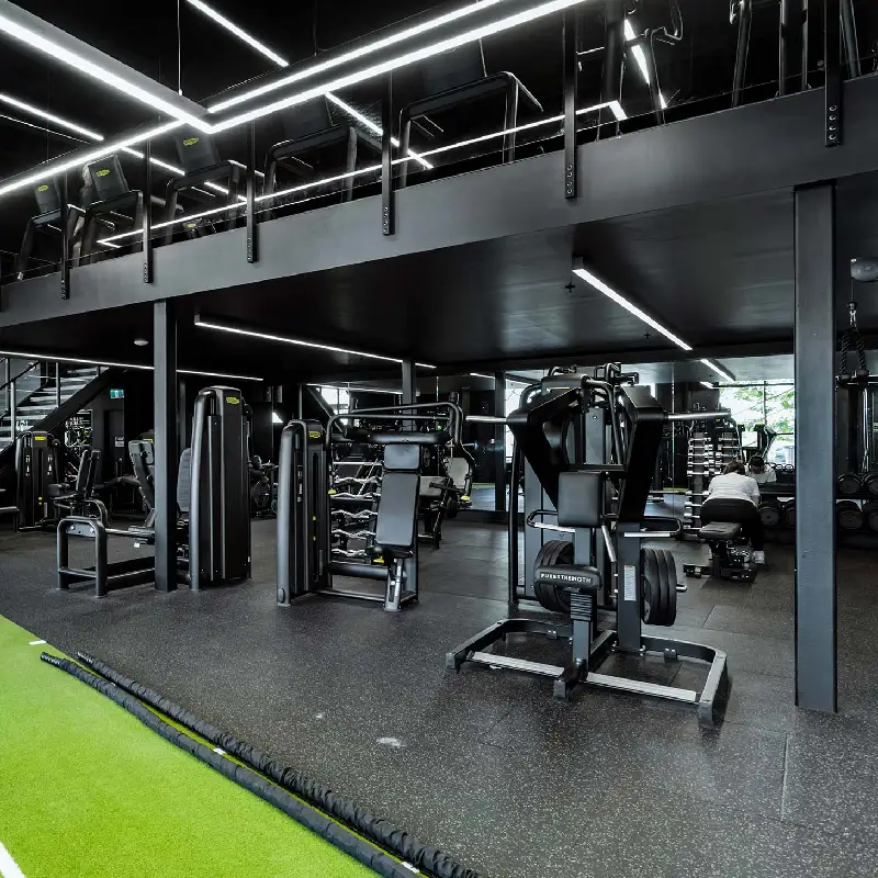 Seamless speckled black rubber gym flooring under heavy strength equipment.