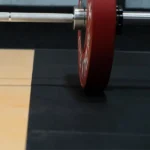 Side view of a red bumper plate on a gym platform