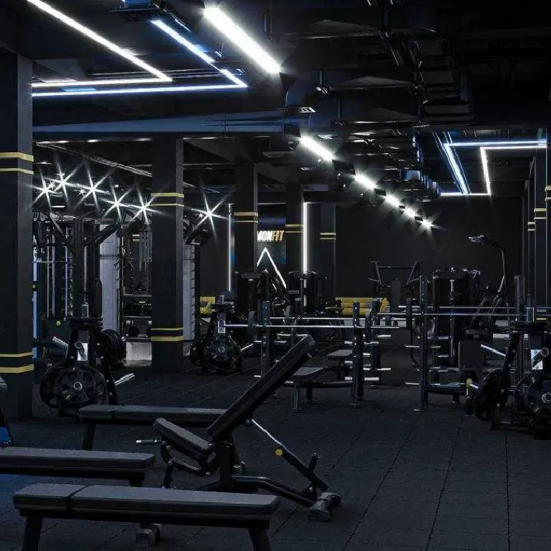 Textured black rubber tile flooring in a dimly lit strength training area.