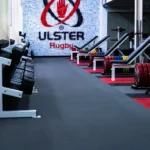 Ulster Rugby weight room with black rubber flooring